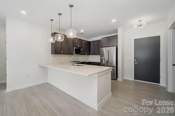 a view of a kitchen with stainless steel appliances granite countertop a sink a refrigerator and a stove