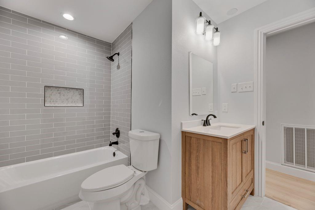 2015 Rose Hill Road Carrollton, TX 75007 - Photo 12 of 19 a bathroom with a toilet a sink a mirror a bathtub and vanity