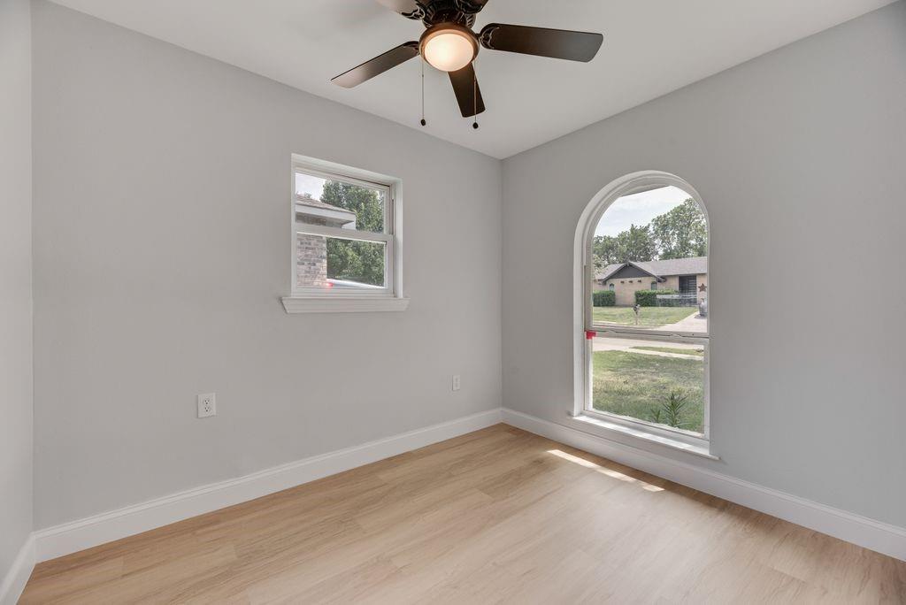 2015 Rose Hill Road Carrollton, TX 75007 - Photo 3 of 19 an empty room with wooden floor chandelier fan and windows