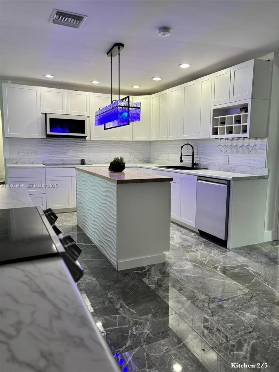 607 Maple Drive Margate, FL 33063 - Photo 25 of 37 a kitchen with stainless steel appliances granite countertop a sink counter space cabinets and a chandelier