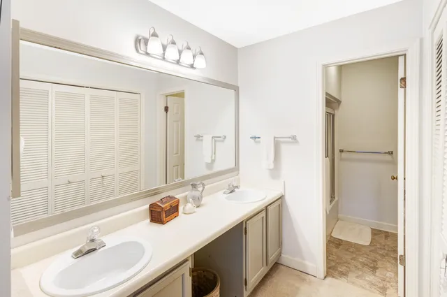 a bathroom with a sink double vanity granite tub shower and a mirror