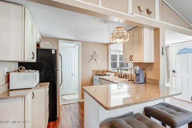 a kitchen with stainless steel appliances granite countertop a refrigerator a stove and white cabinets with wooden floor