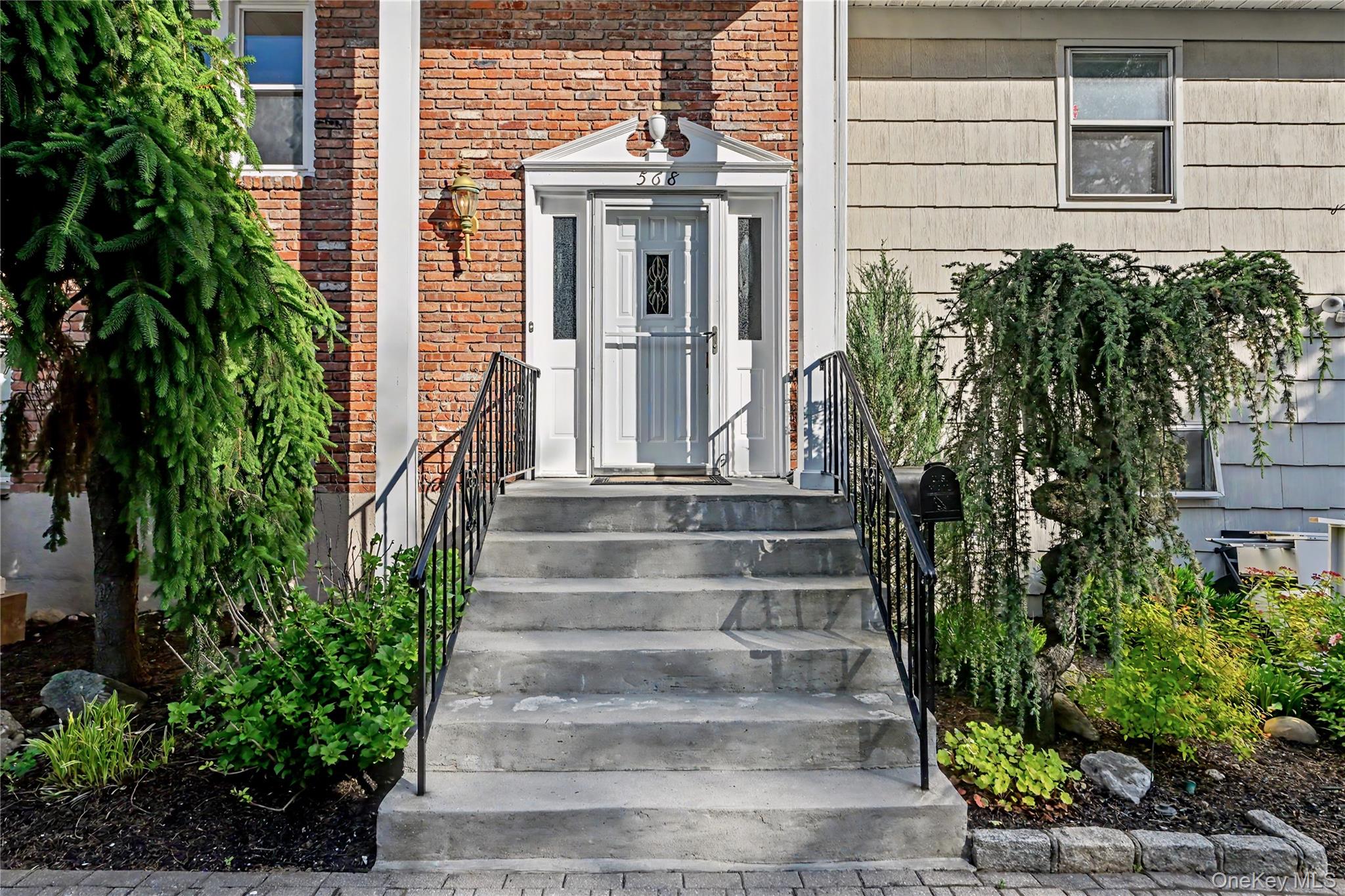 568 Manville Road, Unit UPPER R Pleasantville, NY 10570 - Photo 2 of 32 Front entry featuring concrete steps with wrought iron railings, a white front door with sidelights, and a brick facade