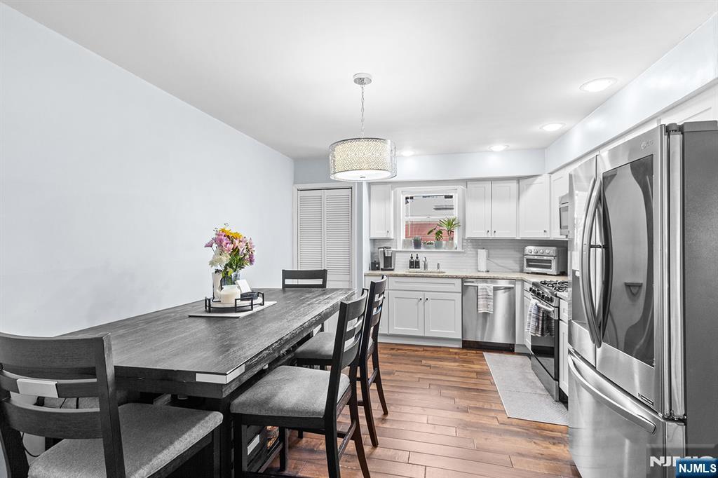 63-69 Rome Street, Unit 5K Newark, NJ 07105 - Photo 5 of 11 a kitchen with stainless steel appliances kitchen island granite countertop a dining table chairs and white cabinets