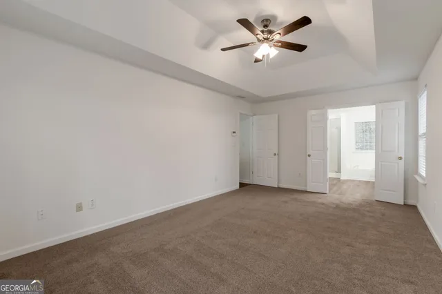 an empty room with closet and a ceiling fan