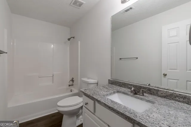 a bathroom with a granite countertop toilet sink and mirror