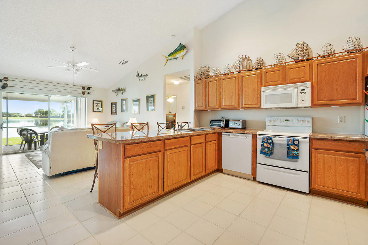 7283 Shell Ridge Terrace Lake Worth, FL 33467 - Photo 9 of 32 a large kitchen with stainless steel appliances granite countertop a stove and a refrigerator