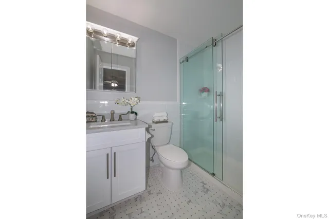 a bathroom with a granite countertop toilet a sink and a mirror