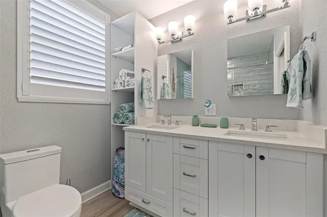 a bathroom with a toilet a sink a mirror and wooden cabinets