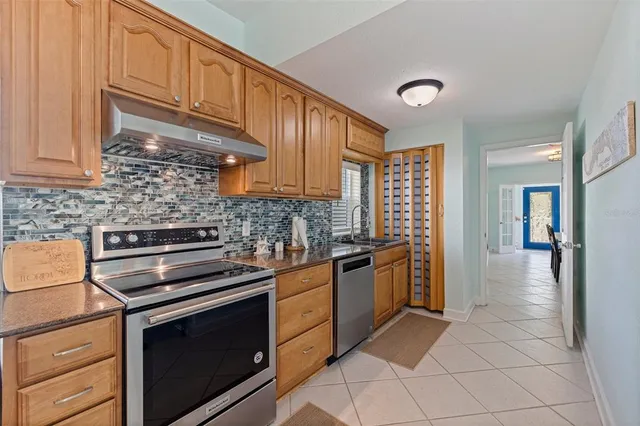 a kitchen with granite countertop a stove cabinets and stainless steel appliances