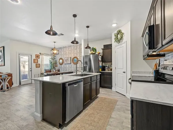 a kitchen with stainless steel appliances granite countertop a sink a stove and a refrigerator