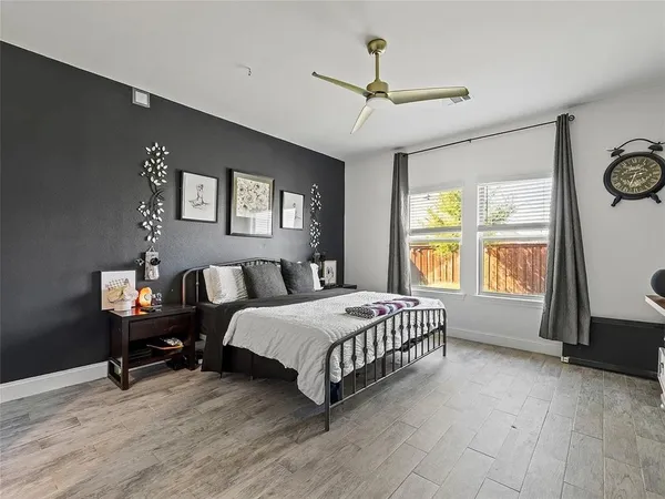 a spacious bedroom with a bed a dresser and paintings on the wall
