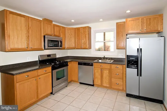 a kitchen with granite countertop a refrigerator stove top oven and sink