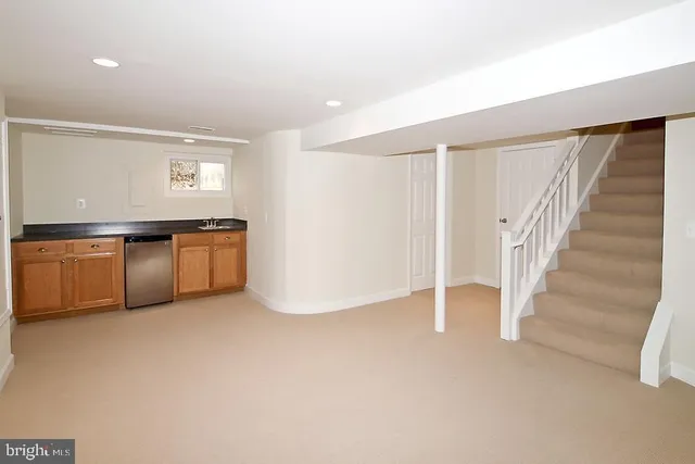 a view of an empty room with wooden floor and stairs