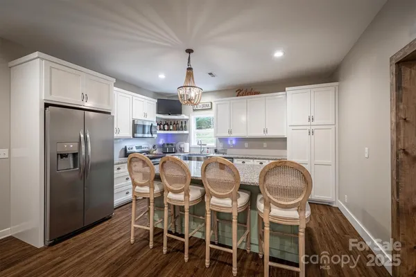 a kitchen with stainless steel appliances a refrigerator a stove a sink and white cabinets with wooden floor