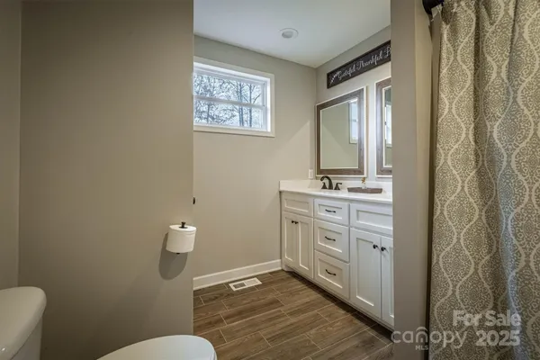 a bathroom with a granite countertop sink mirror vanity and toilet