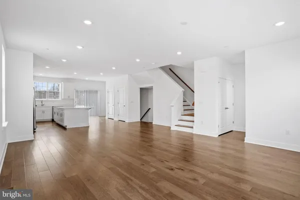 a view of a living room a kitchen with wooden floors and white walls