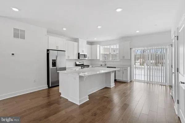 a large white kitchen with wooden floor and a sink