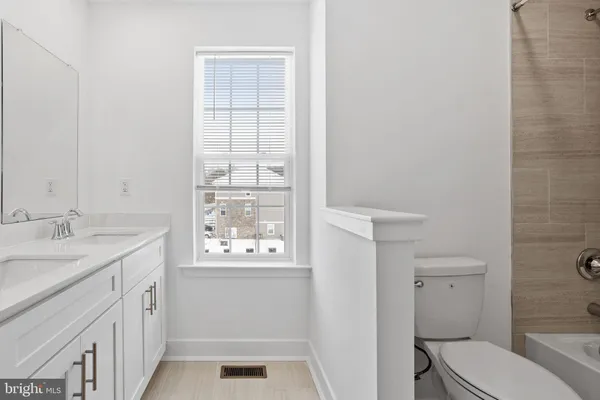 a bathroom with a granite countertop toilet a sink and a window