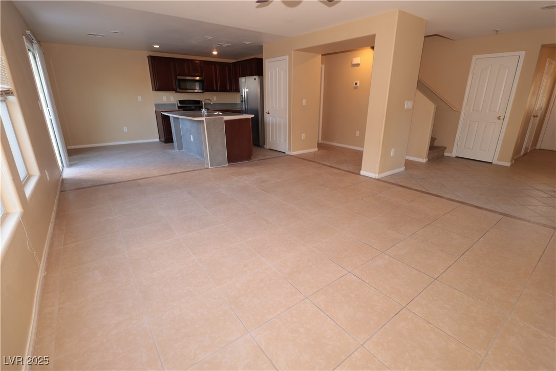5940 Feral Garden Street North Las Vegas, NV 89031 - Photo 30 of 31 Kitchen featuring open floor plan, a kitchen island with sink, light countertops, dark brown cabinets, and light tile patterned flooring