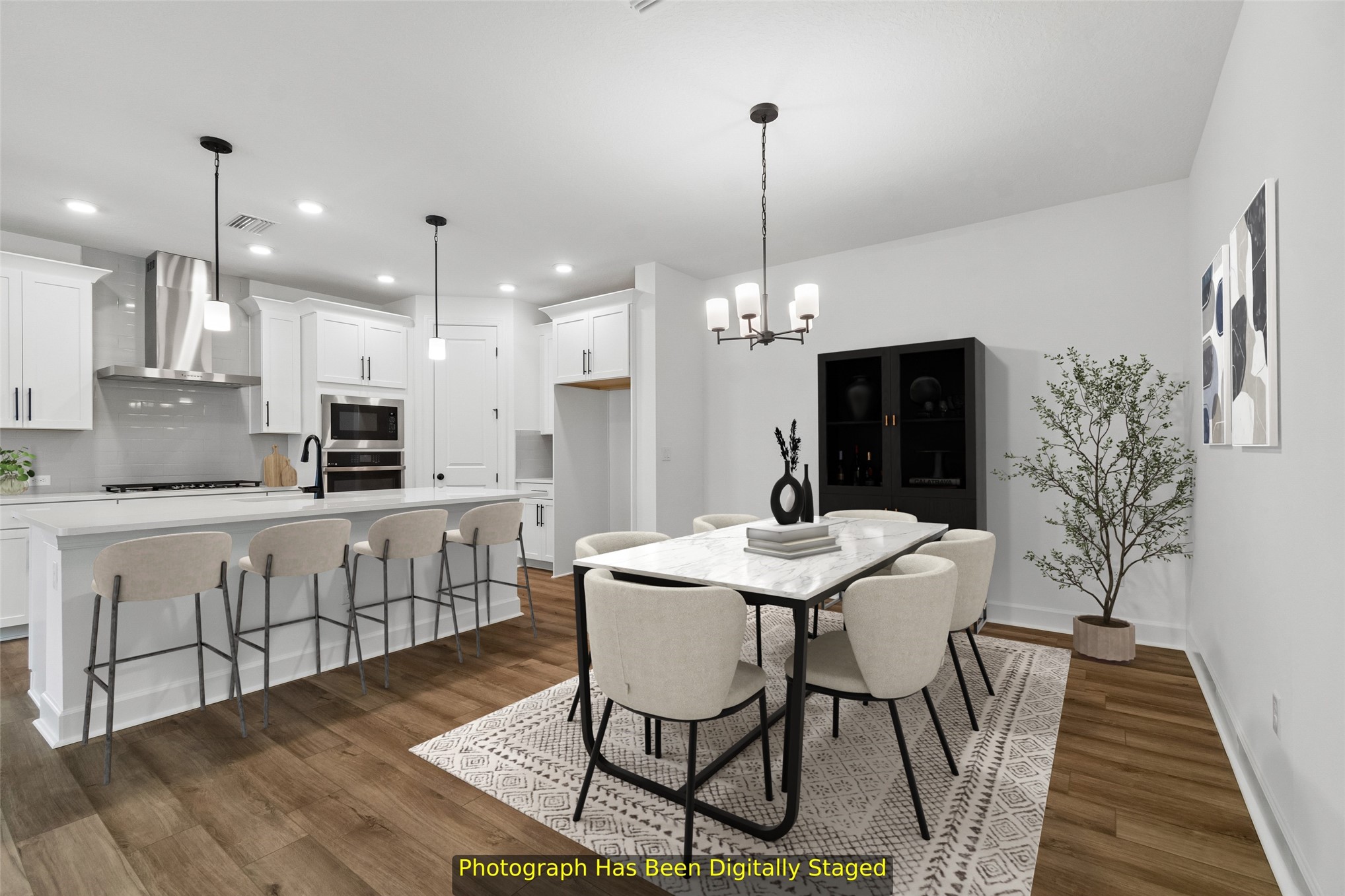 718 Windchime Street Yulee, FL 32097 - Photo 4 of 28 a kitchen with stainless steel appliances kitchen island granite countertop a dining table chairs and white cabinets