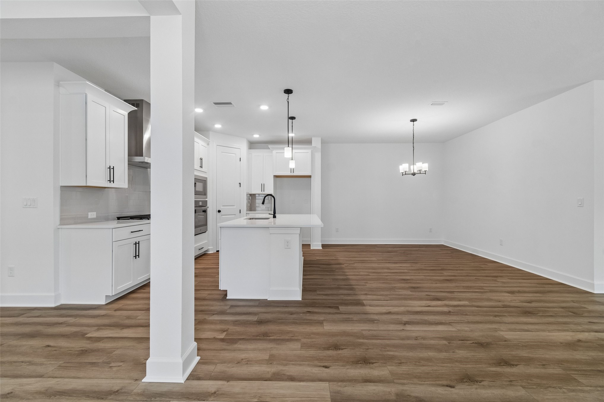 718 Windchime Street Yulee, FL 32097 - Photo 7 of 28 a view of kitchen with white cabinets stainless steel appliances and wooden floor