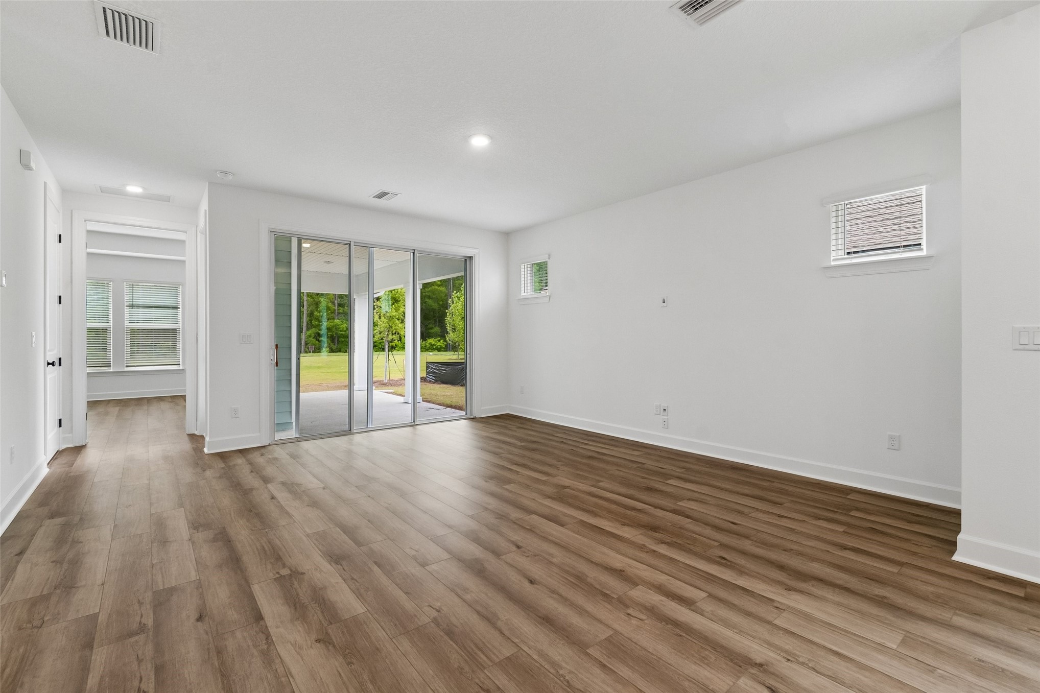 718 Windchime Street Yulee, FL 32097 - Photo 8 of 28 a view of an empty room with wooden floor and a window