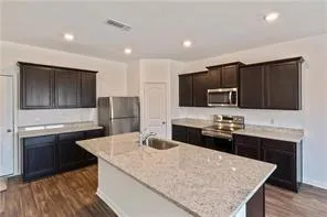 a kitchen with stainless steel appliances granite countertop a sink dishwasher a stove and a refrigerator with wooden floor