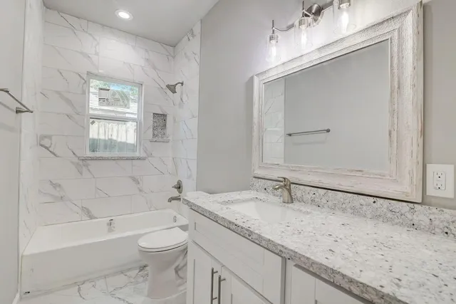 a bathroom with a granite countertop sink a toilet and bathtub