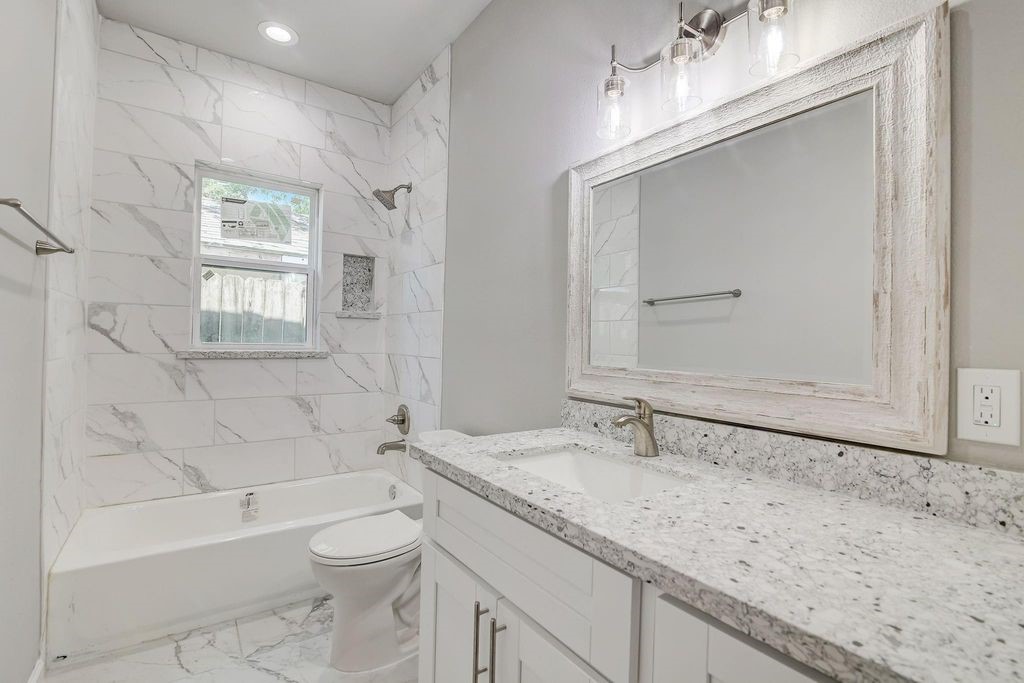 5338 Rapido Road Houston, TX 77033 - Photo 8 of 9 a bathroom with a granite countertop sink a toilet and bathtub