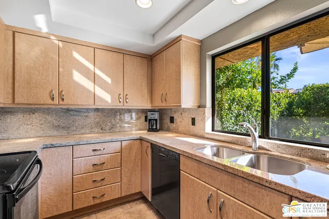 a kitchen with granite countertop a sink window and cabinets