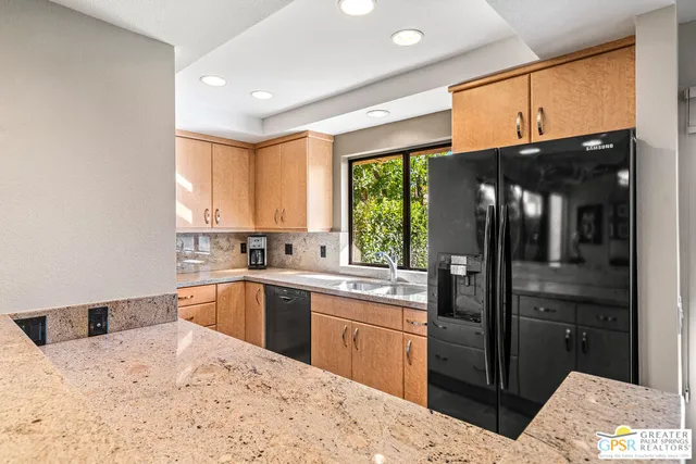 a kitchen with stainless steel appliances kitchen island granite countertop a sink stove and refrigerator