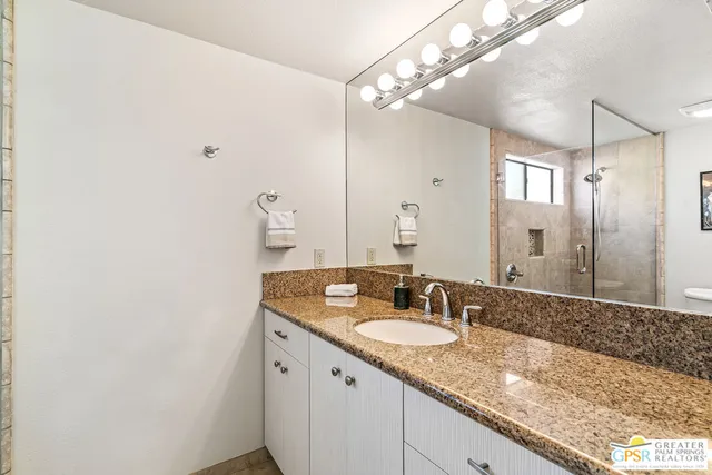a bathroom with a granite countertop sink and a mirror