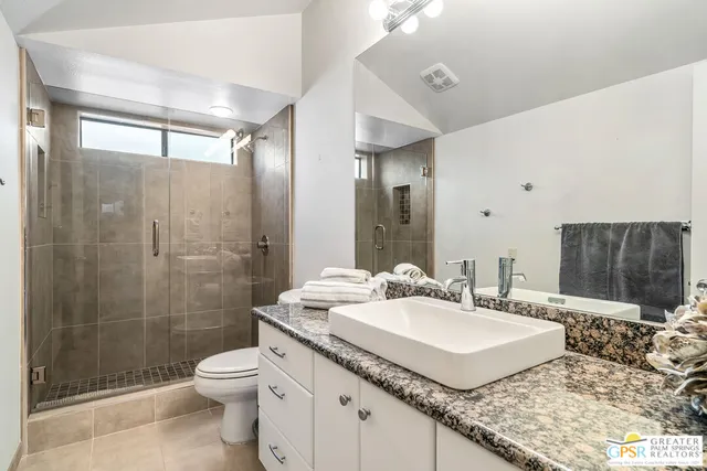a bathroom with a granite countertop sink a toilet a mirror and shower