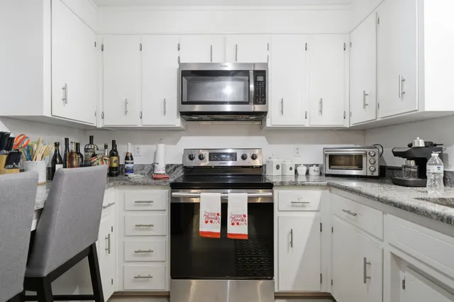 a kitchen with stainless steel appliances granite countertop a stove a sink and a microwave