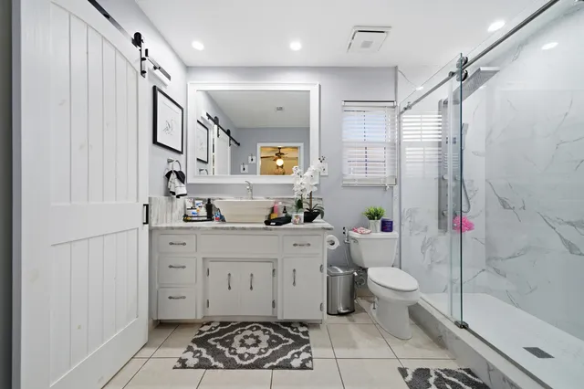 a bathroom with a sink a granite countertop mirror and a shower