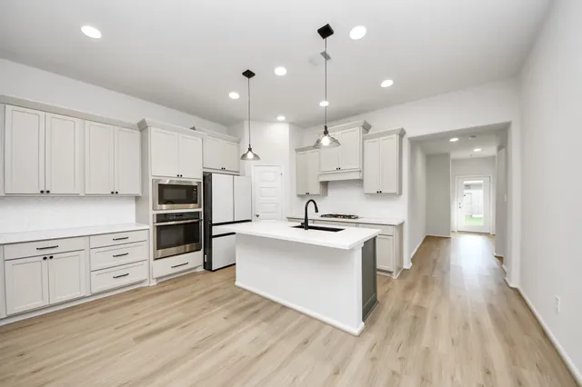 a large kitchen with cabinets wooden floor and stainless steel appliances