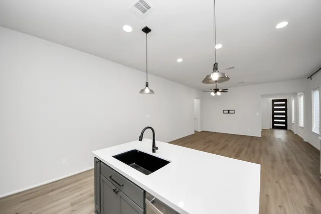 a kitchen with a sink a counter space and wooden floor