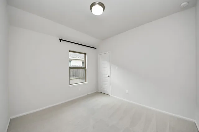 a view of an empty room with window and closet area