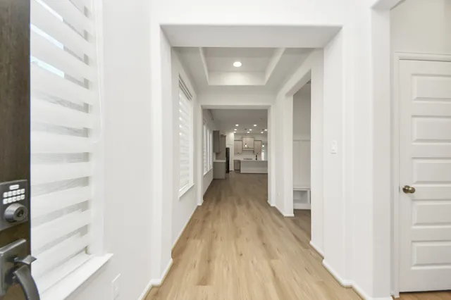 a view of a hallway with wooden floor and a bathroom