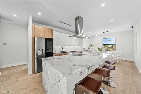 a view of a kitchen with kitchen island stainless steel appliances a stove a sink cabinets and wooden floor