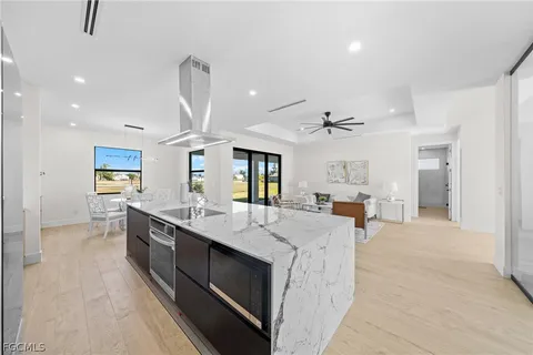 a large white kitchen with a large island oven a sink stainless steel appliances and cabinets