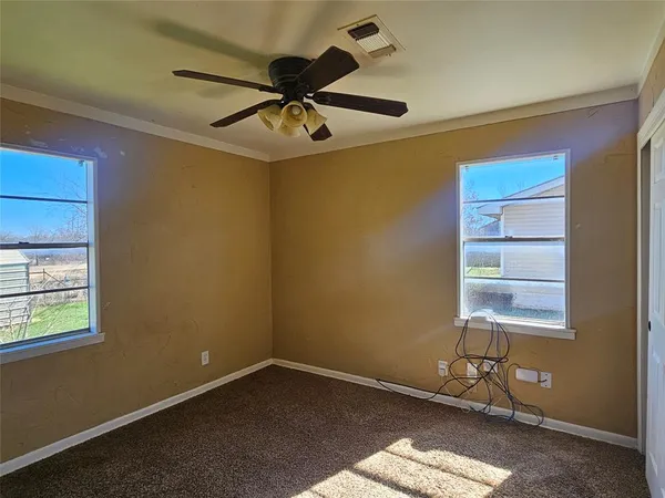 an empty room with windows and fan