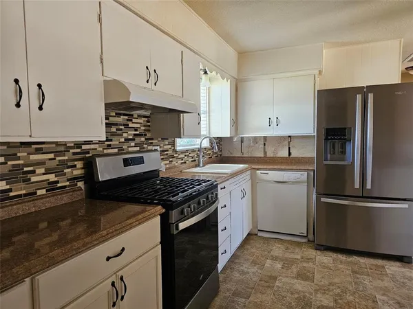 a kitchen with granite countertop a sink stove and refrigerator