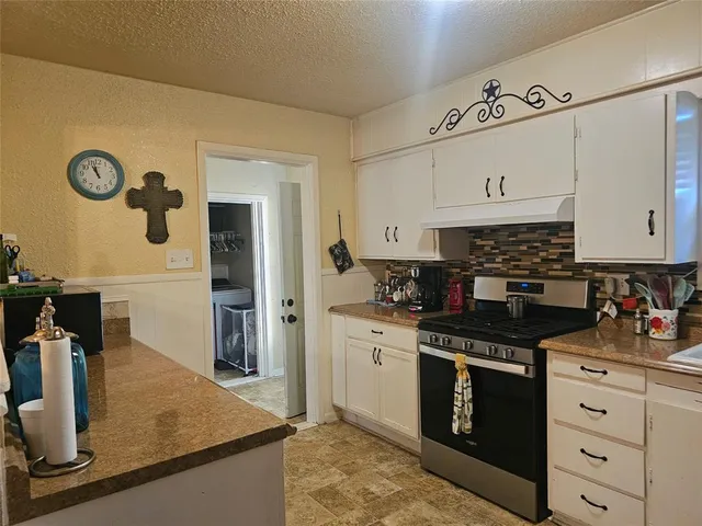 a kitchen with granite countertop a sink a stove and refrigerator
