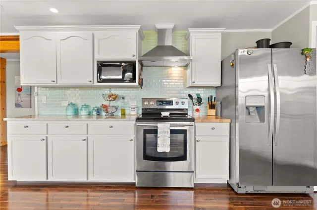 a kitchen with stainless steel appliances granite countertop a refrigerator a stove and a sink with wooden floor