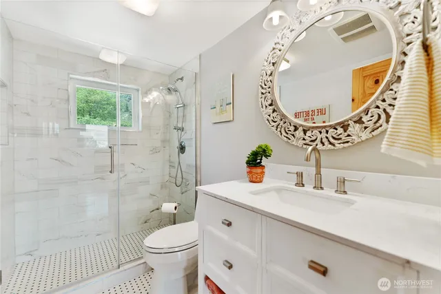 a bathroom with a sink a mirror a toilet and shower