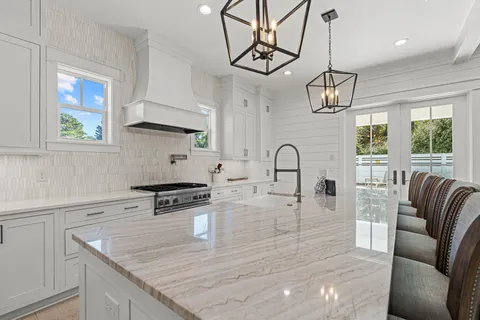 a kitchen with stainless steel appliances granite countertop a stove a sink a refrigerator dining table and chairs with wooden floor