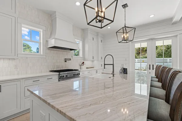 a kitchen with stainless steel appliances granite countertop a stove a sink a refrigerator dining table and chairs with wooden floor