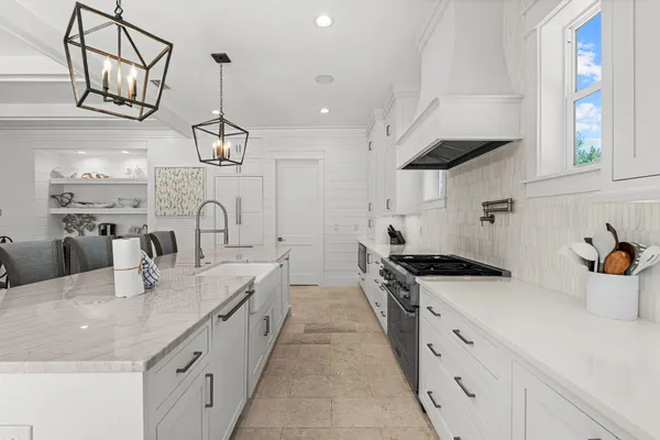a large kitchen with stainless steel appliances a sink a stove and cabinets